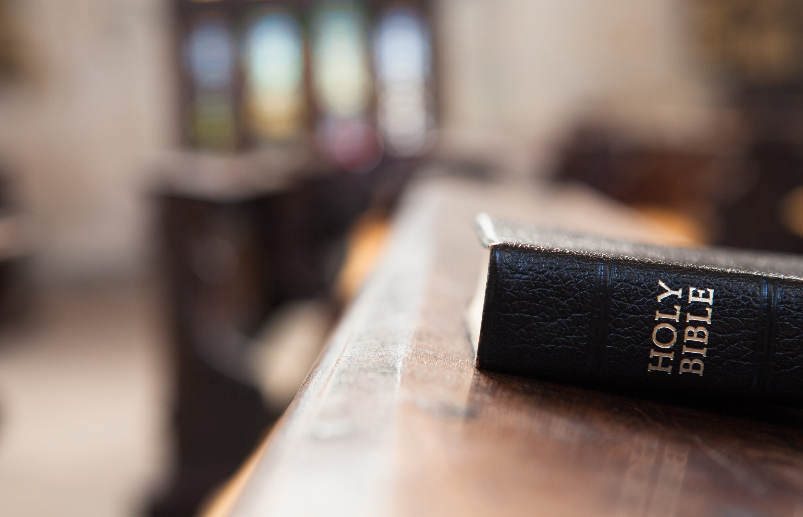 A Holy Bible rests on a wooden surface in a softly blurred interior