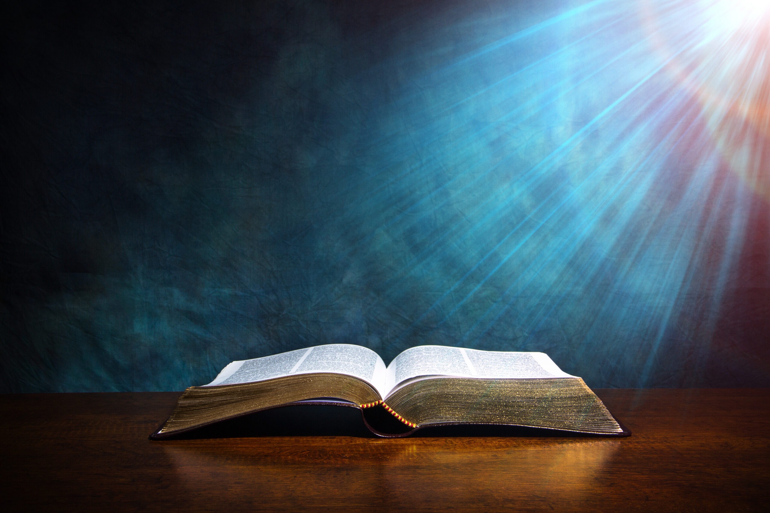 An open book with gilded pages rests on a wooden table